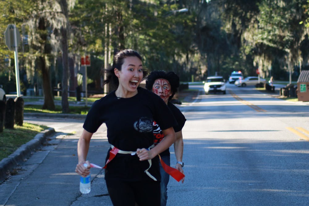 Leeson Chen, a 21-year-old UF computer science sophomore, chases Isabelle Lady, a 20-year-old UF biology junior, as she finishes the last leg of the Gator Zombie 5K. Participants wore flag football belts as they ran while volunteer zombies chased them and tried to pull them off.