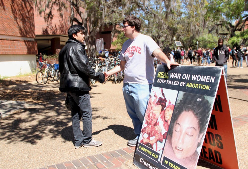 Alfredo Patiño, 22, a UF senior political science and sociology major, and Joe Trammel, 22, a law student from Ohio State University and member of the Created Equal organization, shake hands. Patiño and Trammel had a respectful conversation about the images the Created Equal organization placed on Turlington Plaza on Tuesday.