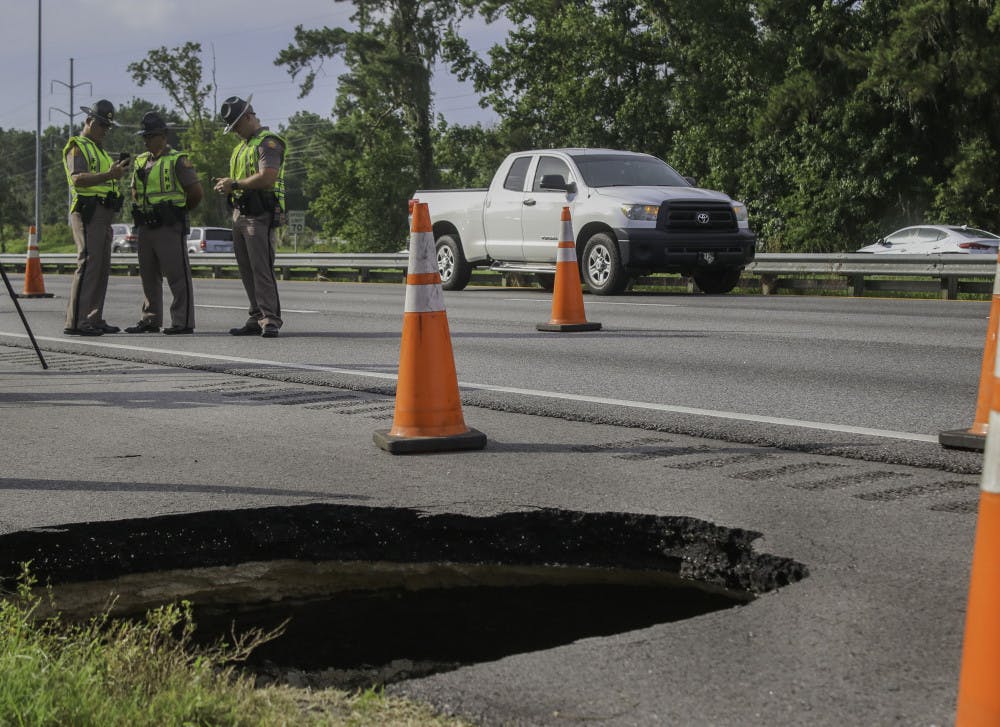 Cars drive by a sinkhole Friday that opened on the southbound shoulder of I-75 near the Williston Road exit, Exit 382. A second sinkhole opened about 40 feet from the first hole between two culverts. The Florida Department of Transportation is evaluating if the holes are connected and the stability of the road.