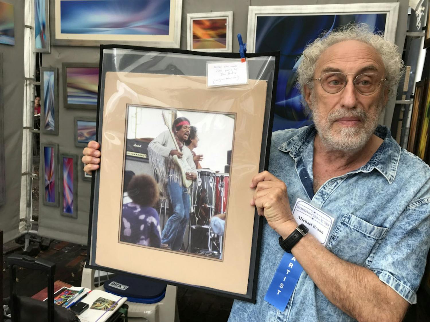 Michael Braun, an artist at the 37th Annual Downtown Festival &amp; Art Show, holds a picture of Jimi Hendrix wearing clothes Braun designed at Woodstock.
&nbsp;