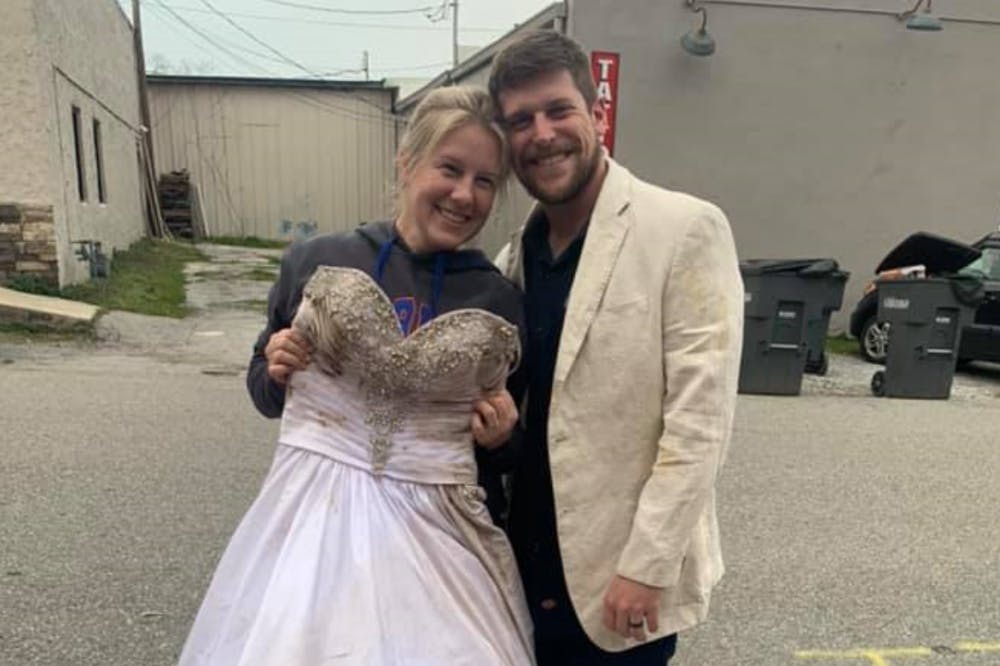 Lauren Hampton Farmer, 31, holds her wedding dress that was found after tornadoes in Cookeville, Tennessee destroyed her house and spread out her belongings in early March. Her husband, Kory Farmer, is wearing his wedding blazer that was also found in the aftermath, alongside her UF diploma. She graduated from UF in 2010.