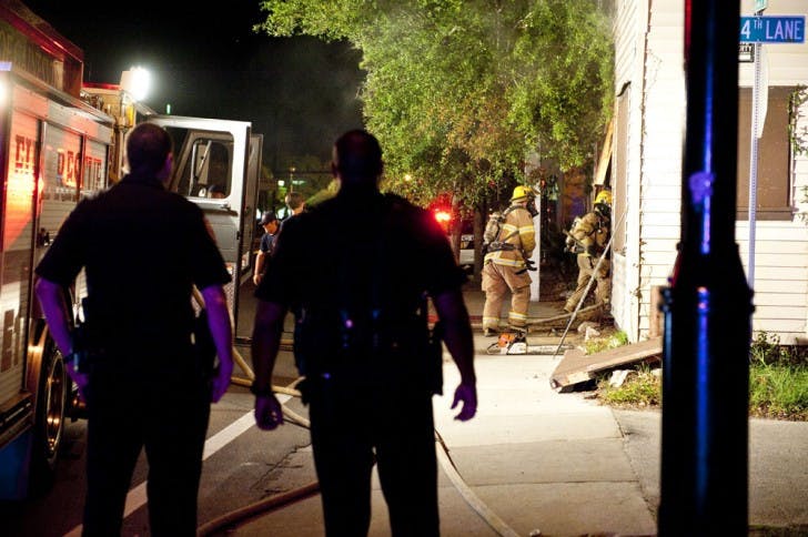 Gainesville Police officers look on as Gainesville Fire Rescue workers enter a building on Northwest 13th Street late Tuesday night.