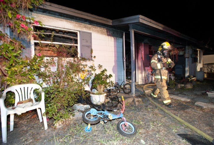 A firefighter walks out of a burned house at 3818 NE 12th St. Fire Rescue District Chief Richard Saulsberry said five adults and two children lived in the house, but only one elderly woman was home at the time of the incident.