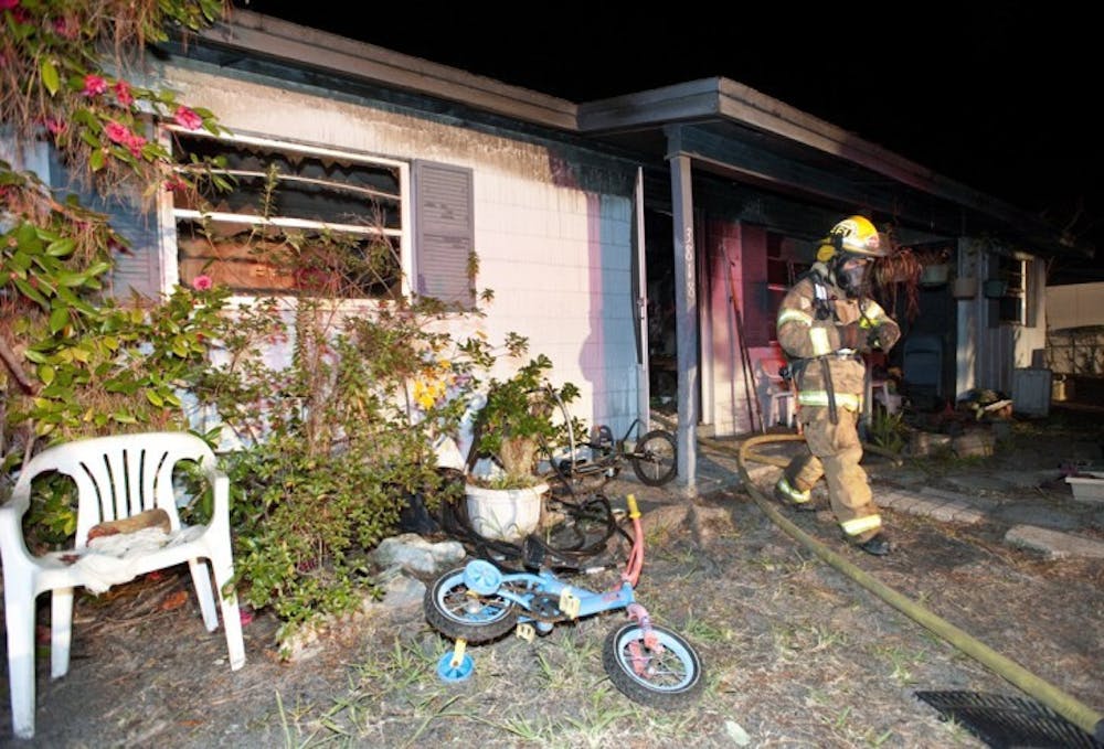 <p>A firefighter walks out of a burned house at 3818 NE 12th St. Fire Rescue District Chief Richard Saulsberry said five adults and two children lived in the house, but only one elderly woman was home at the time of the incident.</p>