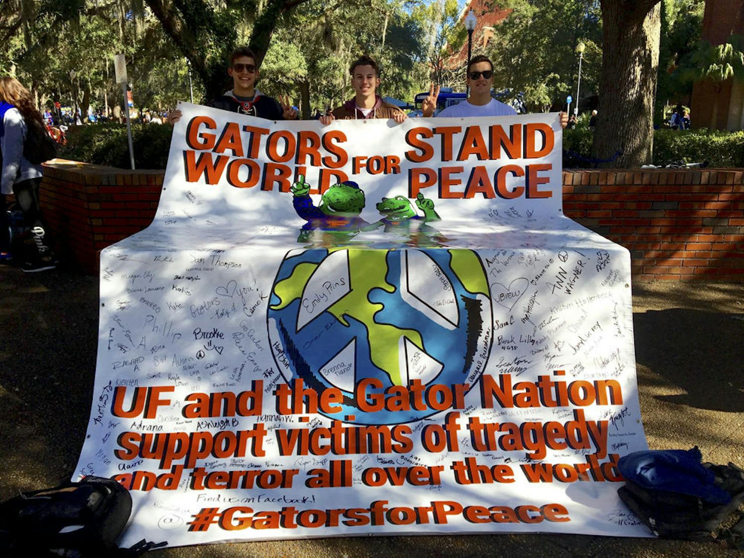 Students from Gators for Peace present their sign at Turlington Plaza on Tuesday, encouraging others to sign it in support of their cause.