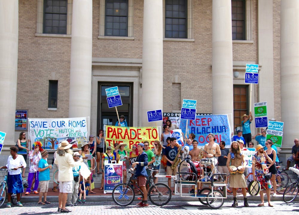 About 70 people, clad in tie-dye shirts and carrying bongos and banners, pause by the Hippodrome State Theatre on Saturday during the Parade to the Polls. They were supporting local Alachua politicians Mike Byerly and Robert Hutchinson.