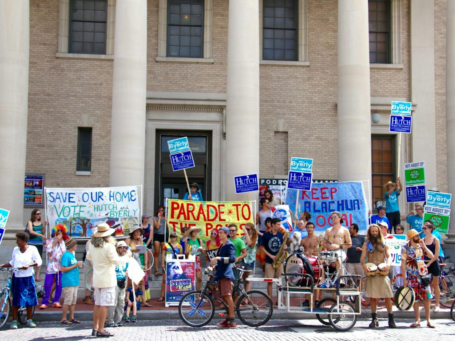 About 70 people, clad in tie-dye shirts and carrying bongos and banners, pause by the Hippodrome State Theatre on Saturday during the Parade to the Polls. They were supporting local Alachua politicians Mike Byerly and Robert Hutchinson.