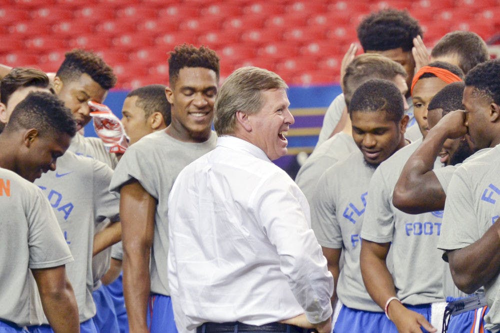<p>UF coach Jim McElwain laughs with players after practice on Dec. 4, 2015, prior to the SEC Championship Game in Atlanta.</p>