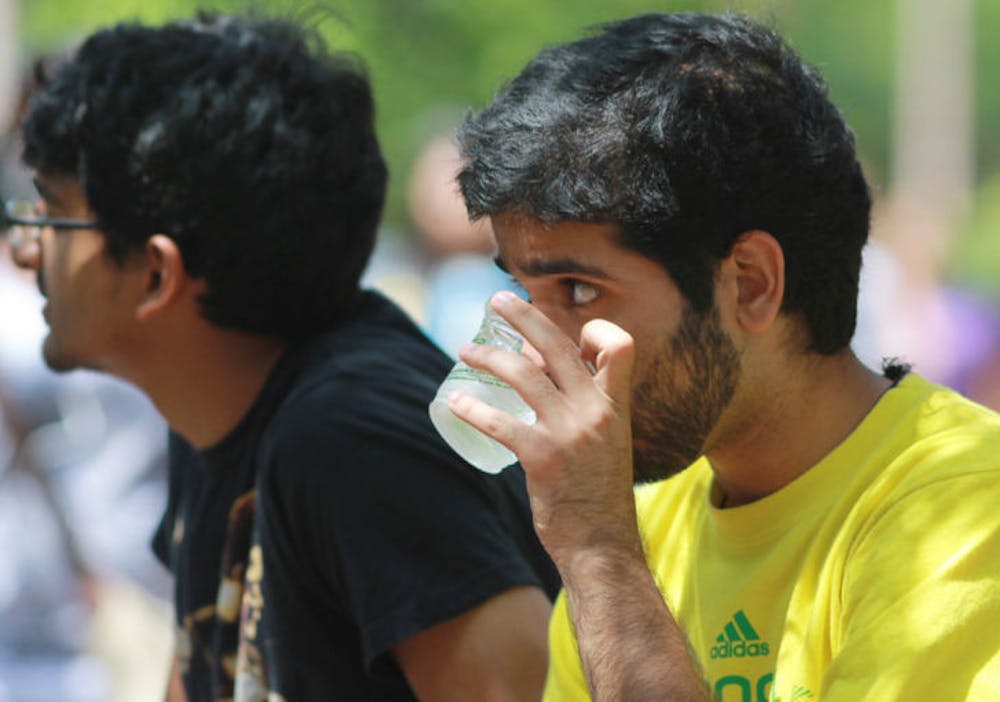 <p>UF behavioral and cognitive neuroscience junior Ram Peesapati, 20, right, sips from a cup of water Thursday afternoon on Turlington Plaza. Students are encouraged to stay hydrated throughout gameday weekend.</p>