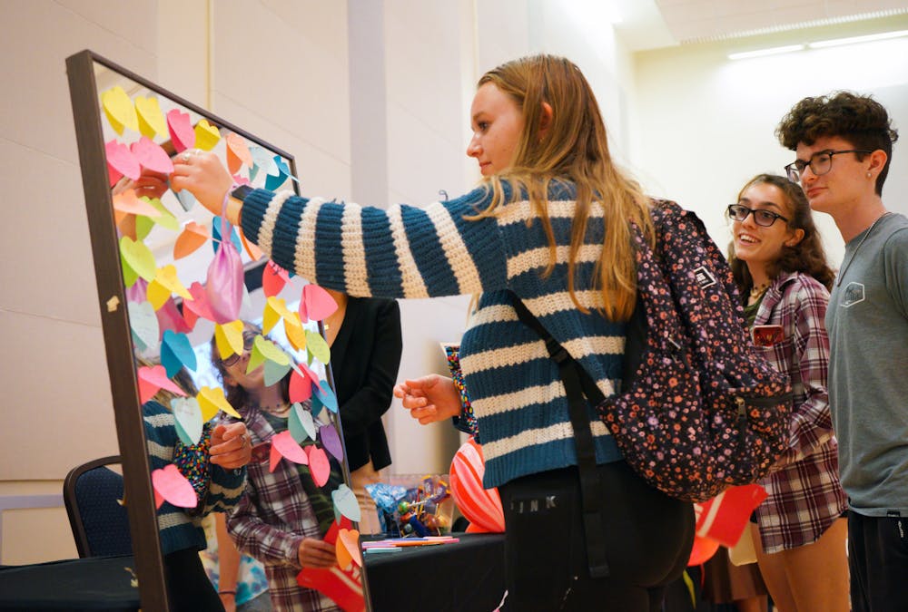 <p>Brooke Dinicola places a sticky note with a body-positive message on a mirror at Sex in the Swamp, an event held at the Reitz Union to promote safe sex practices among college students, Tuesday, March 28, 2023.</p>