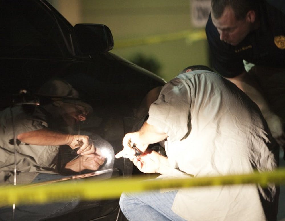 <p>Gainesville Police officers inspect a black Nissan Altima outside of Club Decadence, located off Southwest Second Avenue. The car was involved in a shooting on Sunday night.</p>