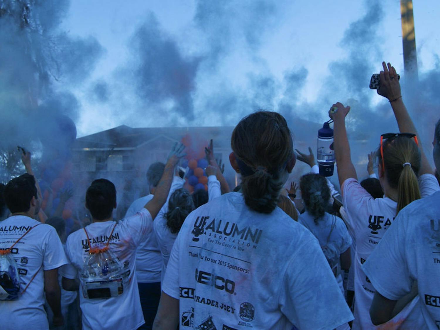Runners throw blue powder in the air during the Gator Run after-party on Flavet Field Saturday evening.