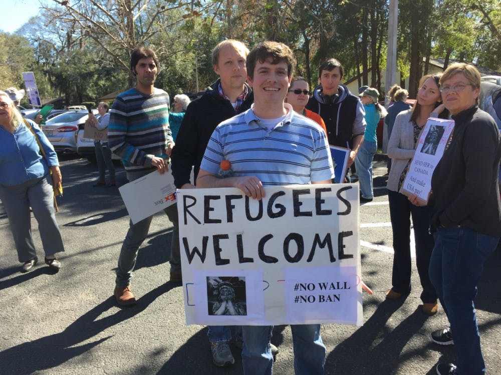 More than 100 people gathered outside Rep. Ted Yoho's office on Tuesday with signs to protest President Donald Trump's administration.