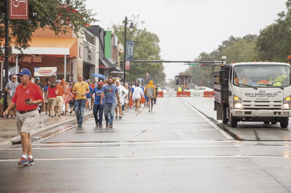 Despite the rain, fans walk down the closed-off University Avenue to Ben Hill Griffin Stadium on Saturday afternoon for the UF Homecoming football game.