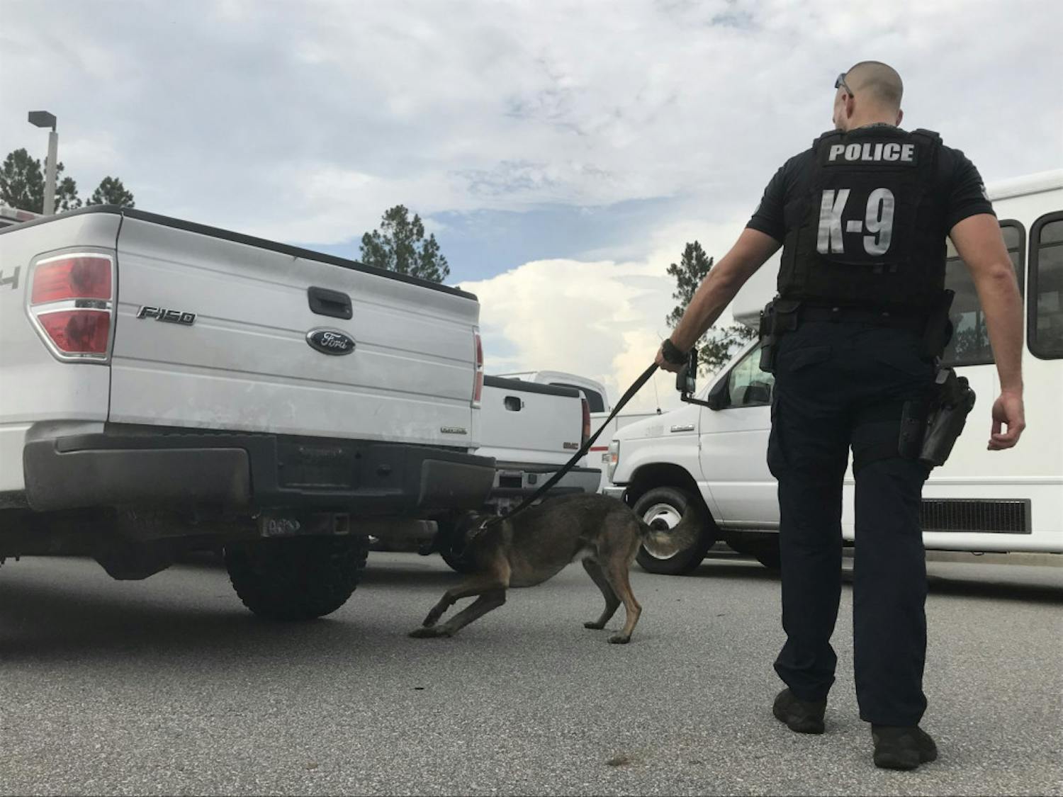 Ares sniffs at the car where a narcotics scent was planted while his handler, Cpl. Hayes-Morrison, watches.
