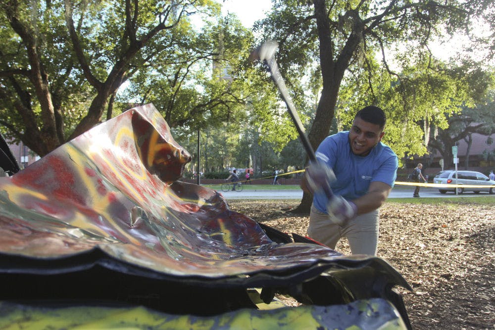 <p>Mausam Trivedi, a 21-year-old UF hospitality junior and president of the Sigma Beta Rho Fraternity, takes a swing at an FSU-colored car during the SOS Smash fundraiser.</p>