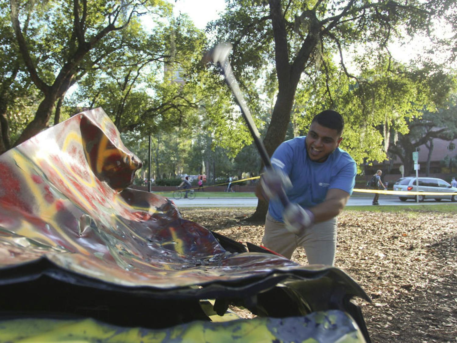 Mausam Trivedi, a 21-year-old UF hospitality junior and president of the Sigma Beta Rho Fraternity, takes a swing at an FSU-colored car during the SOS Smash fundraiser.