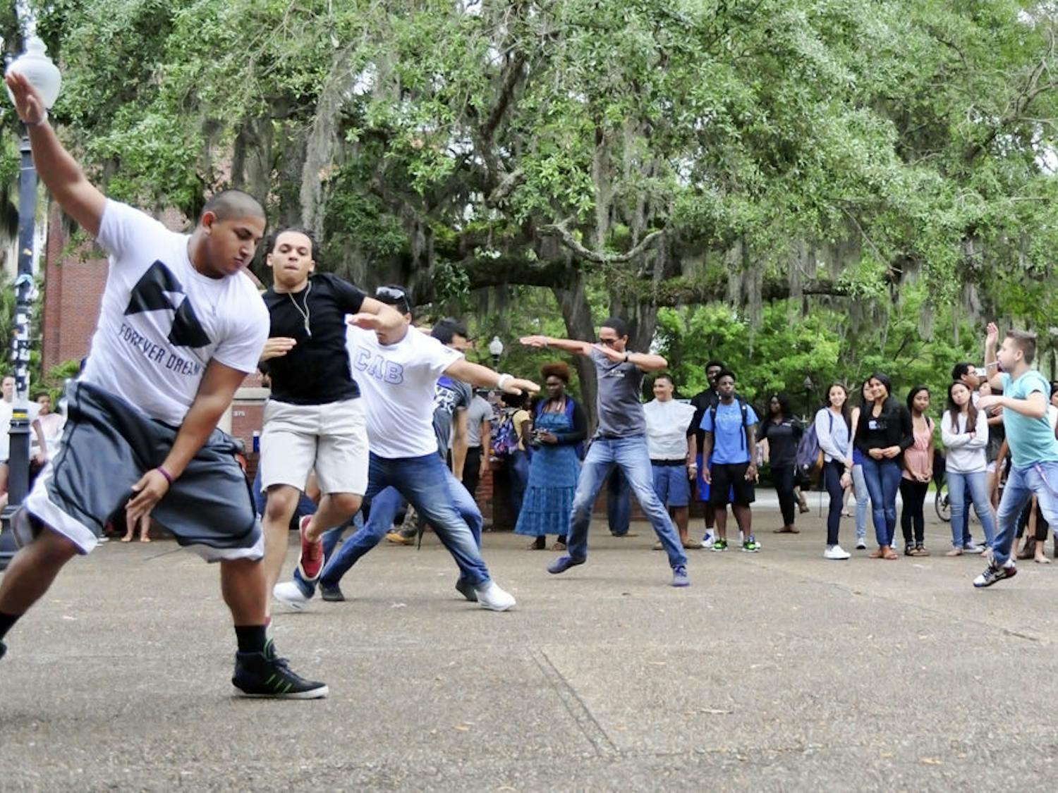 Carlos Soria (left), a 21-year-old anthropology student, leads members of Sigma Lambda Beta through a step routine during a Fourth Friday showcase in Turlington Plaza on Friday.
