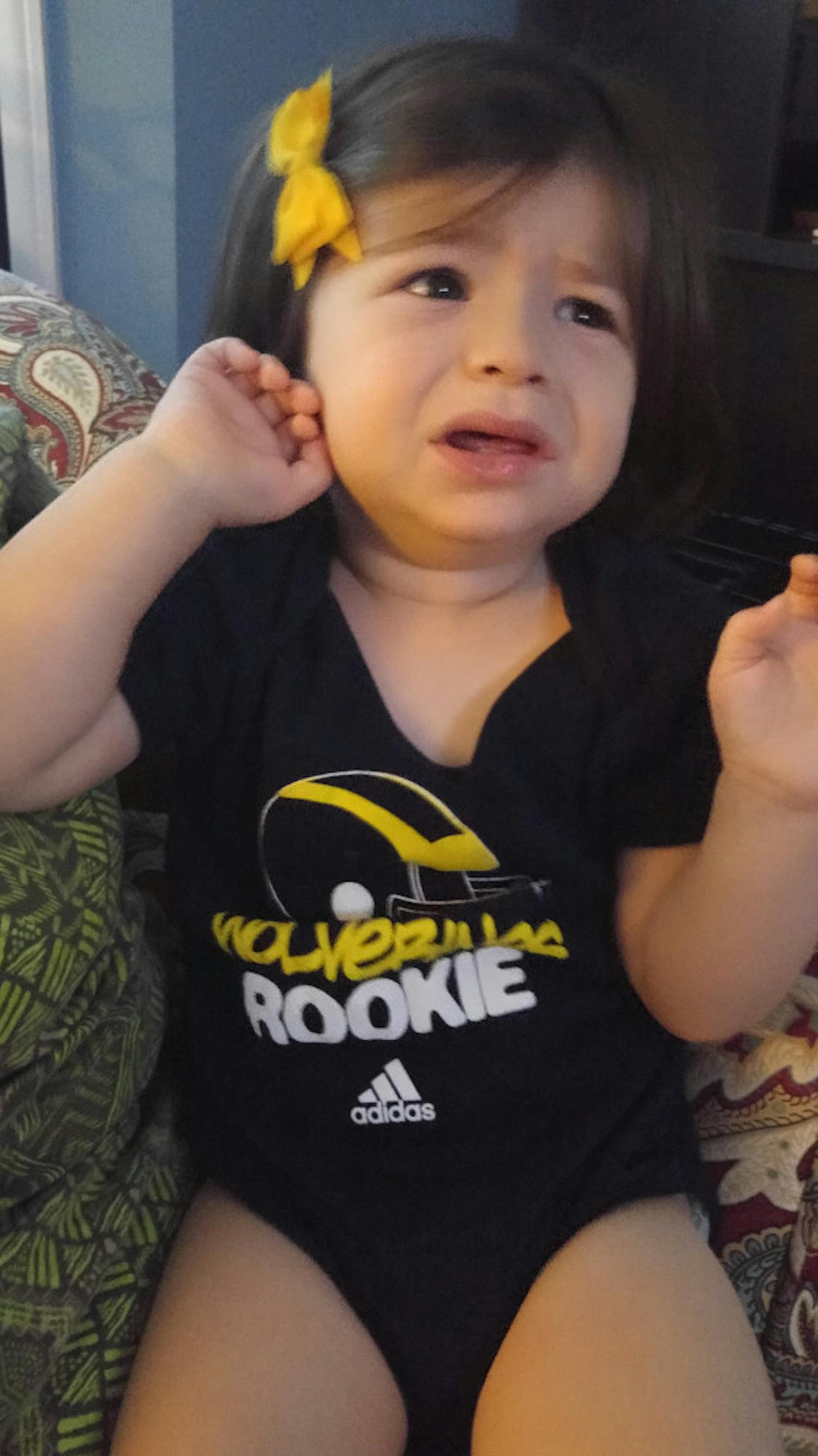 Lily, the daughter of tormented Gator fan Daniel Stone, offers an uncomfortable expression while wearing Michigan apparel.