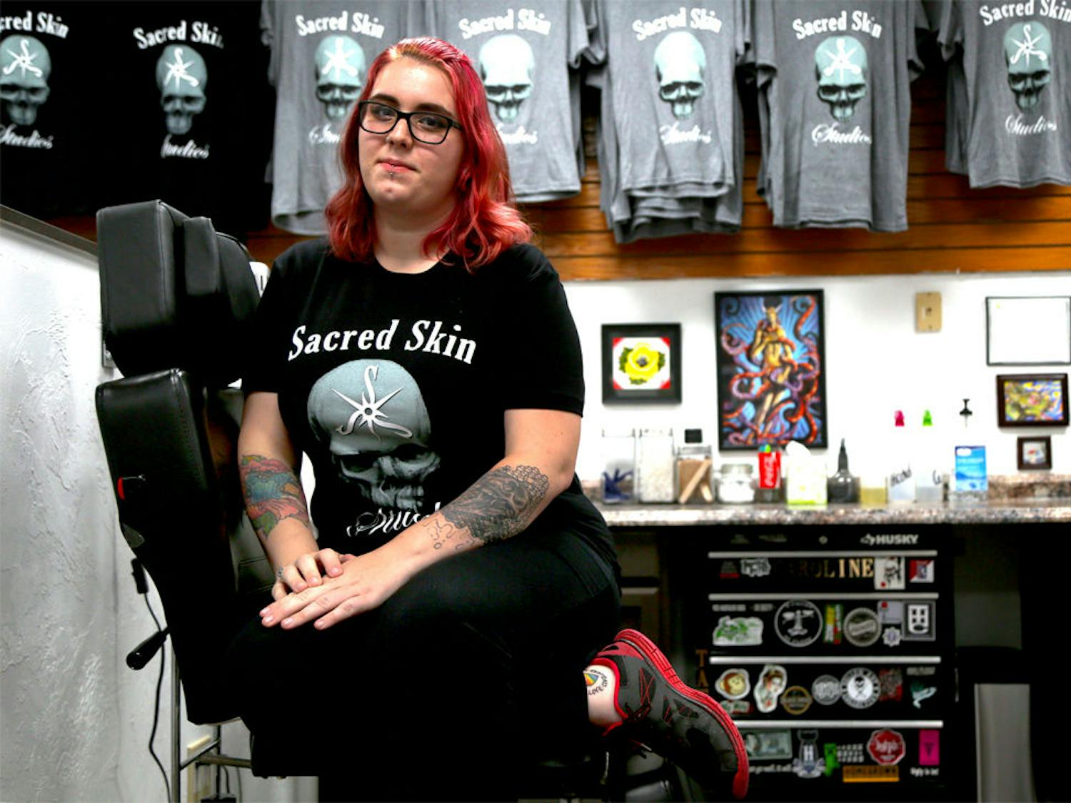 Caroline Phillpot, a 25-year-old tattoo artist, poses in the shop she works in, Sacred Skin Studios, where she is offering tattoos of a rainbow heart with the words “Love Conquers Hate,” for $50. She started the initiative after the shooting in an Orlando nightclub and will donate 50 percent of the proceeds to the Support Victims of Pulse Shooting GoFundMe page by Equality Florida.