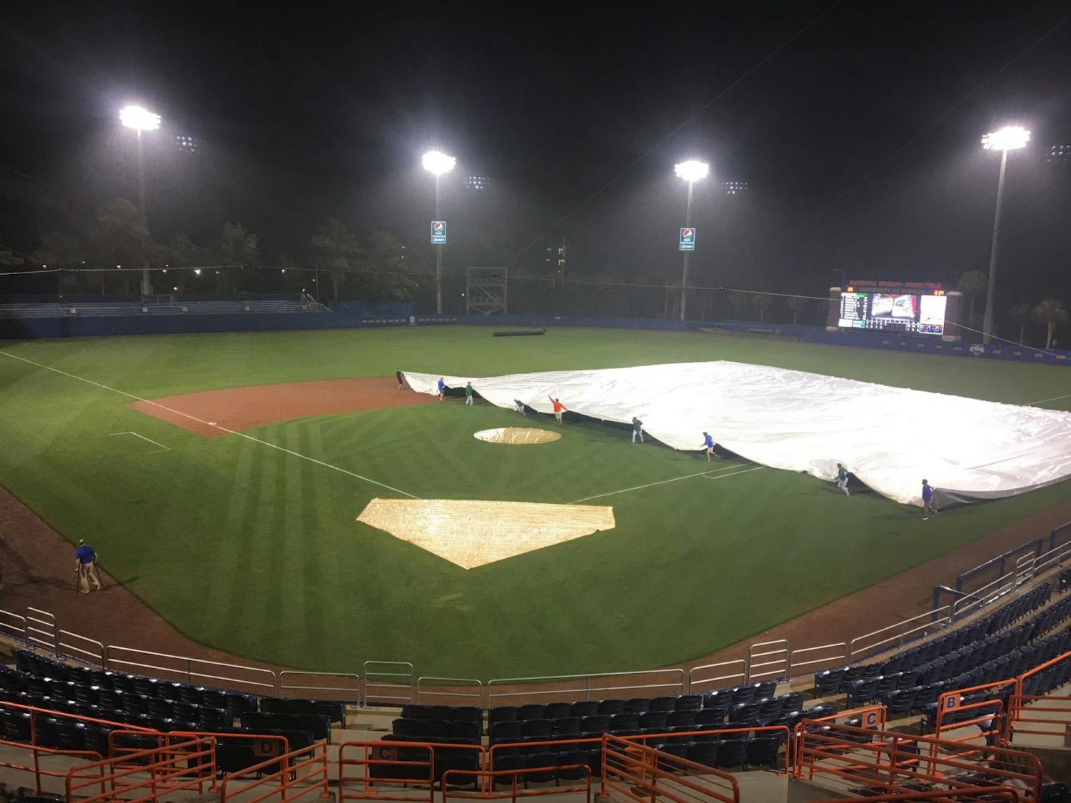 The tarp is pulled over the field as rain falls at McKethan Stadium during Florida's canceled game against Stetson on Tuesday night.
