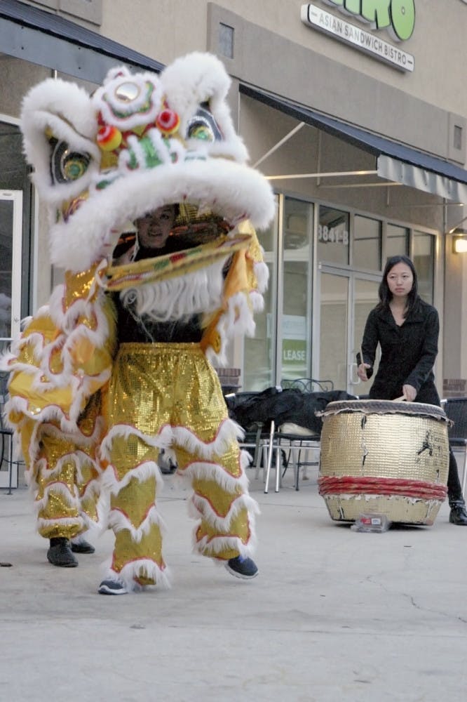 Xuan Ooi, an 18-year-old UF freshman, peers through the mouth of her lion costume as she performs a lion dance to the sound of the drum outside Bento Cafe on Archer Road on Thursday. Jia-Uei Chen, also an 18-year-​old UF freshman, sets the beat for the dance, which celebrates Chinese New Year.Correction: Jia-Uei Chen's name was originally misspelled.
