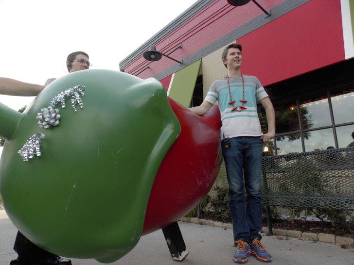 Daniel Helfrich, a 19-year-old UF classics junior, stands in front of his replacement pepper as Chili’s representatives watch the occasion. His former chili was stolen.