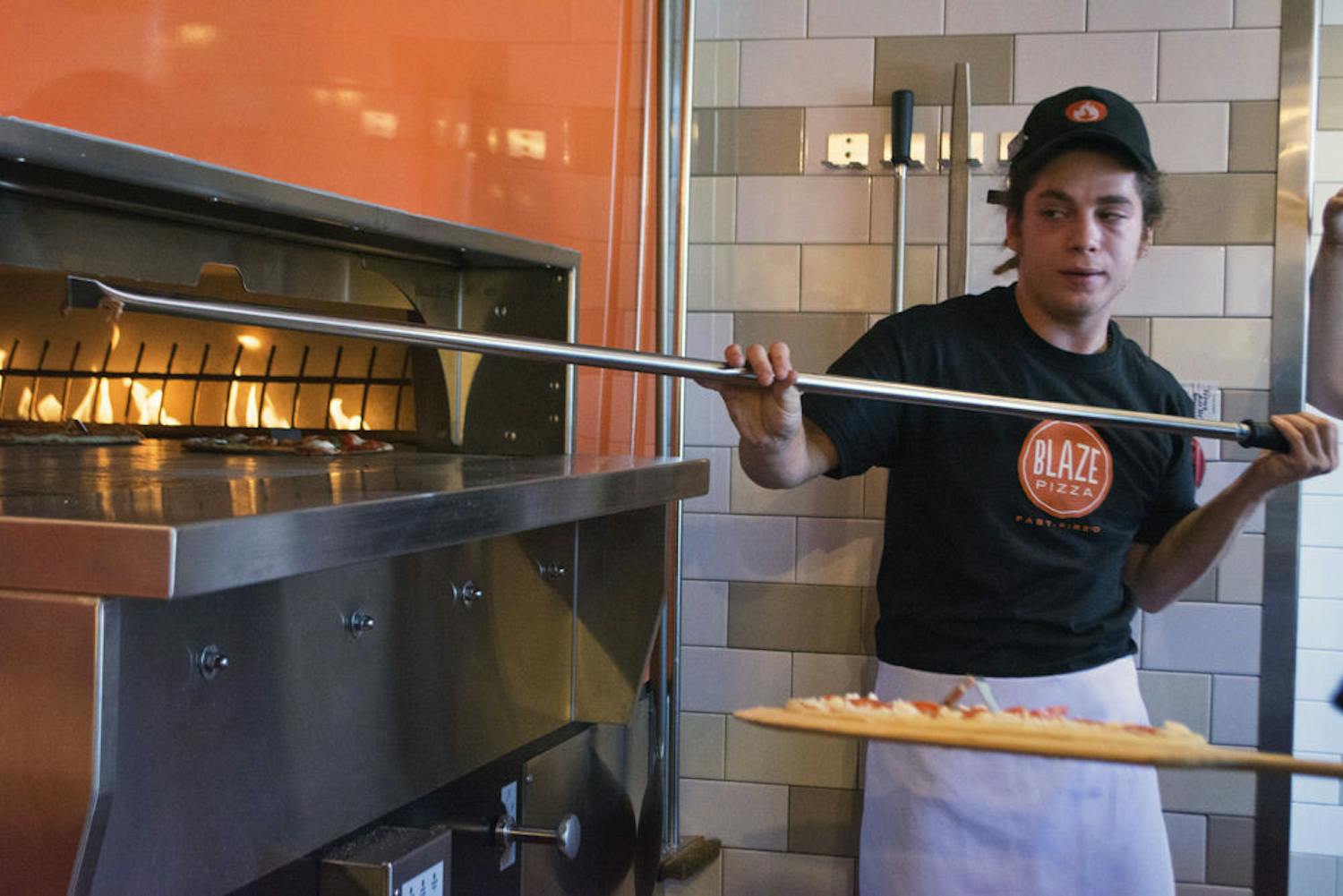 Blaze Fast-Fire’d Pizza employee Dallas Witters, 23, turns pizza in an oven using a long paddle at the joint’s meet-and-greet event Wednesday.