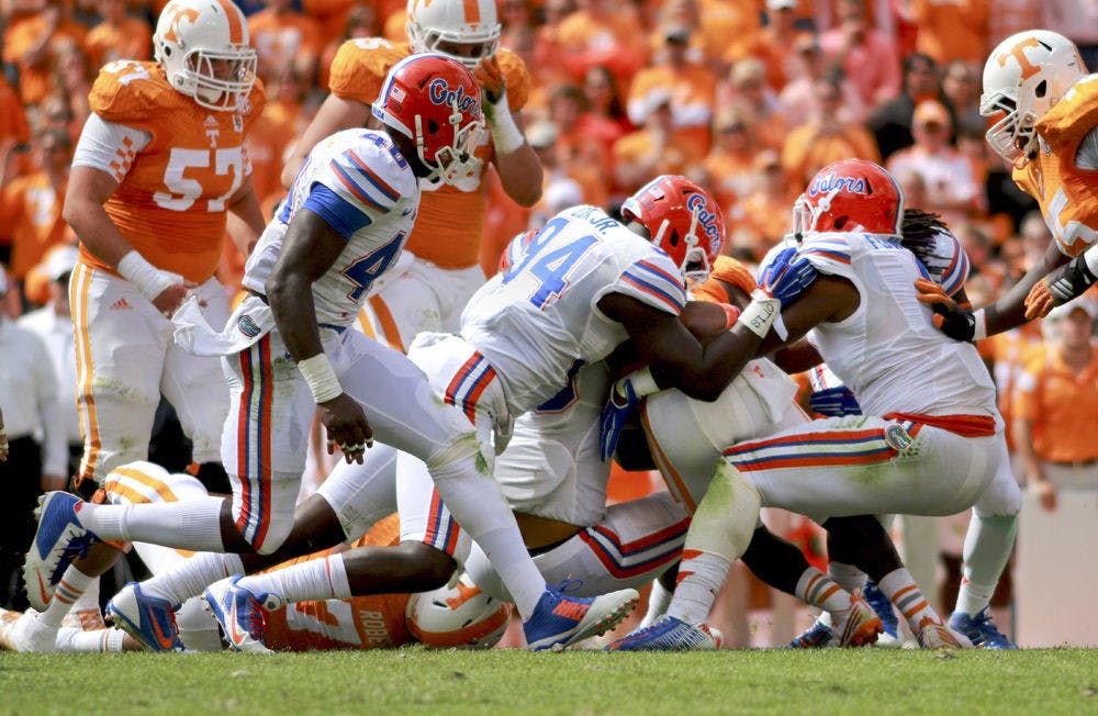 Redshirt sophomore defensive end Bryan Cox Jr. helps tackle a Tennessee player during Florida's 10-9 victory against Tennessee on Saturday at Neyland Stadium in Knoxville.