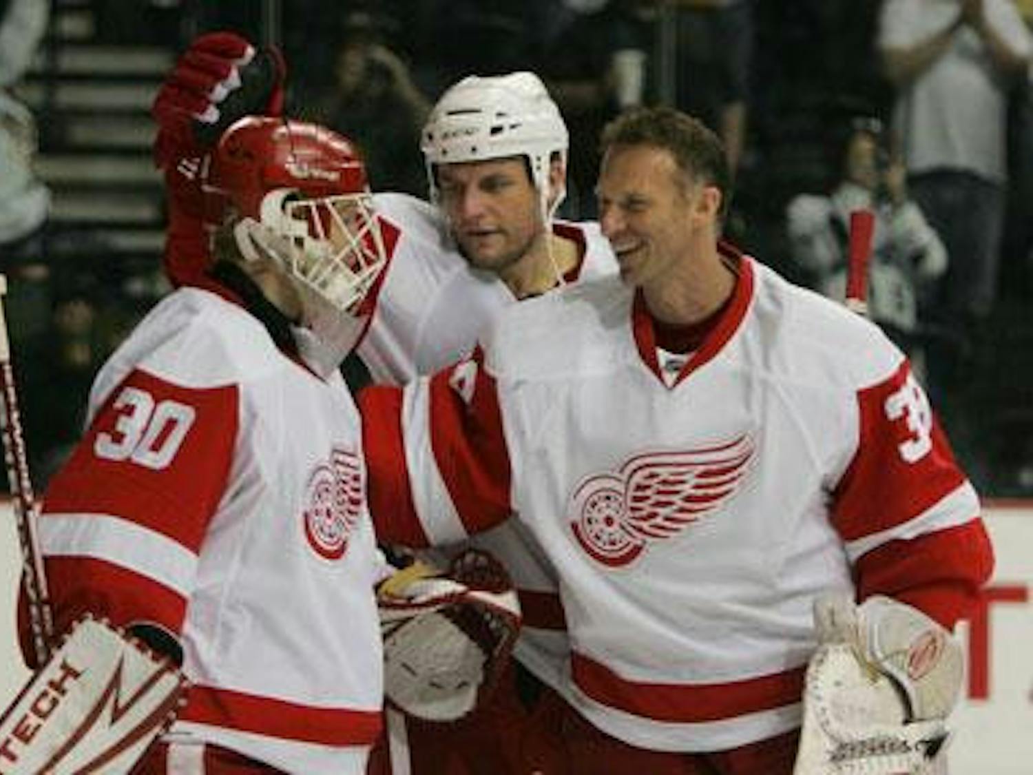 Detroit goalie Chris Osgood (left) is congratulated by teammates Darren McCarty (center) and Dominik Hasek on his shutout against Nashville on Sunday. The Red Wings won 3-0 and took the series, 4-2.