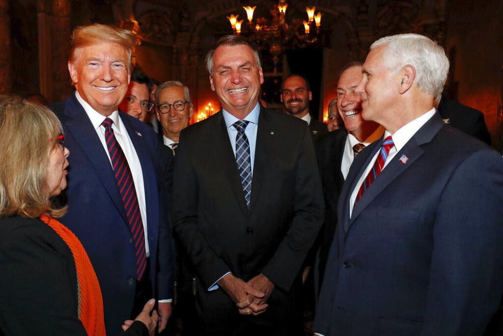 In this March 7, 2020 photo provided by Brazil's presidential press office, Brazil's President Jair Bolsonaro, center, stands with President Donald Trump, second from left, Vice President Mike Pence, right, and Brazil's Communications Director Fabio Wajngarten, behind Trump partially covered, during a dinner in Florida. Wajngarten tested positive for the new coronavirus, just days after the trip, according to Bolsonaro's communications office on Thursday, March 12, 2020. (Alan Santos/Brazil's Presidential Press Office via AP)