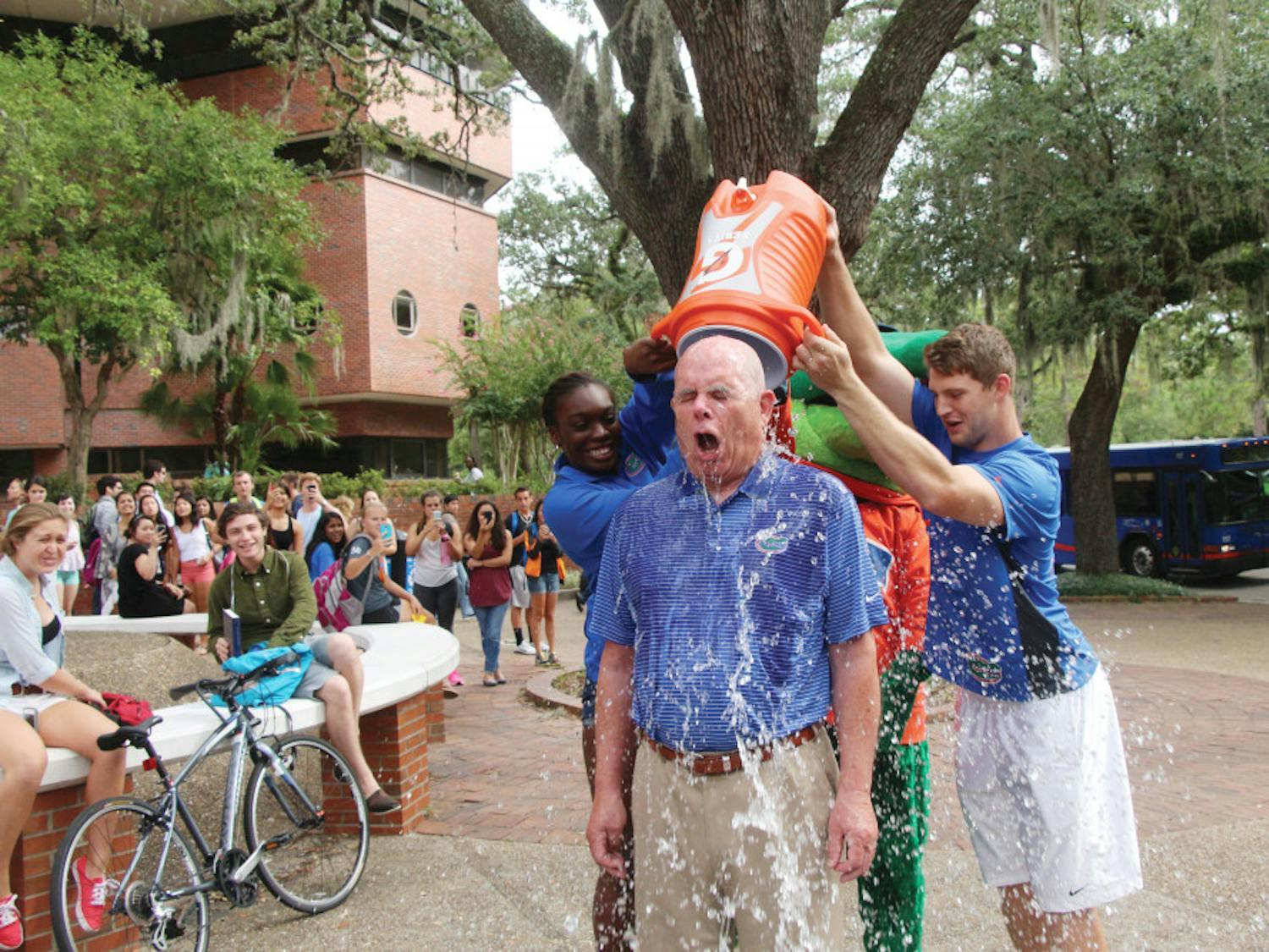 Gator volleyball blocker Simone Antwi and Gator quarterback Jeff Driskel dump ice water on UF President Bernie Machen on Turlington Plaza on Monday. The ALS Ice Bucket Challenge raises awareness of the disease and collects donations.