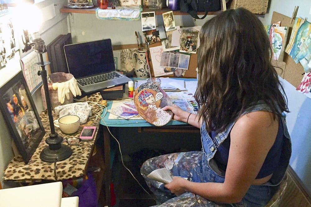 Horner examines one of her pieces in her Gainesville studio; though she makes art to sell, she also makes art for pleasure, like the piece she holds.