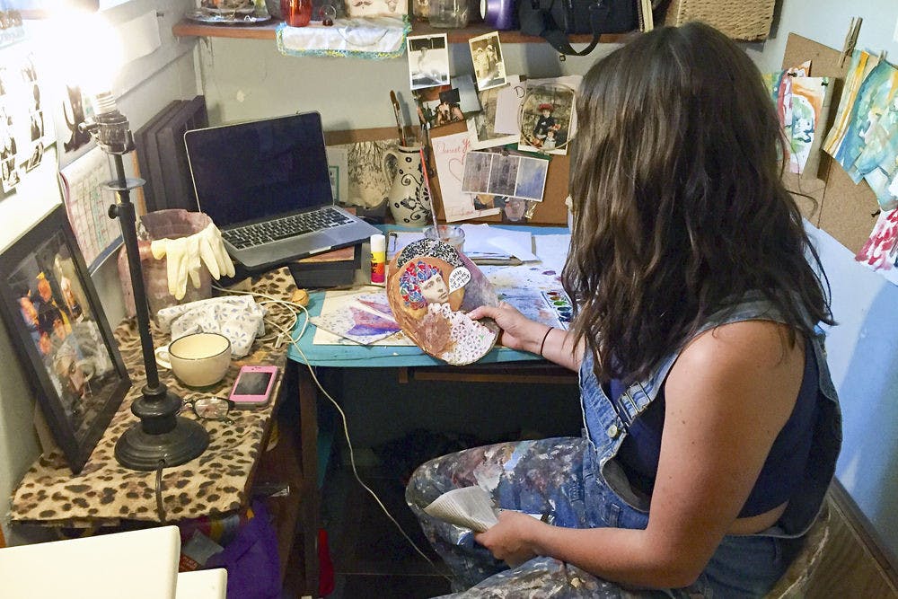 <p>Horner examines one of her pieces in her Gainesville studio; though she makes art to sell, she also makes art for pleasure, like the piece she holds.</p>