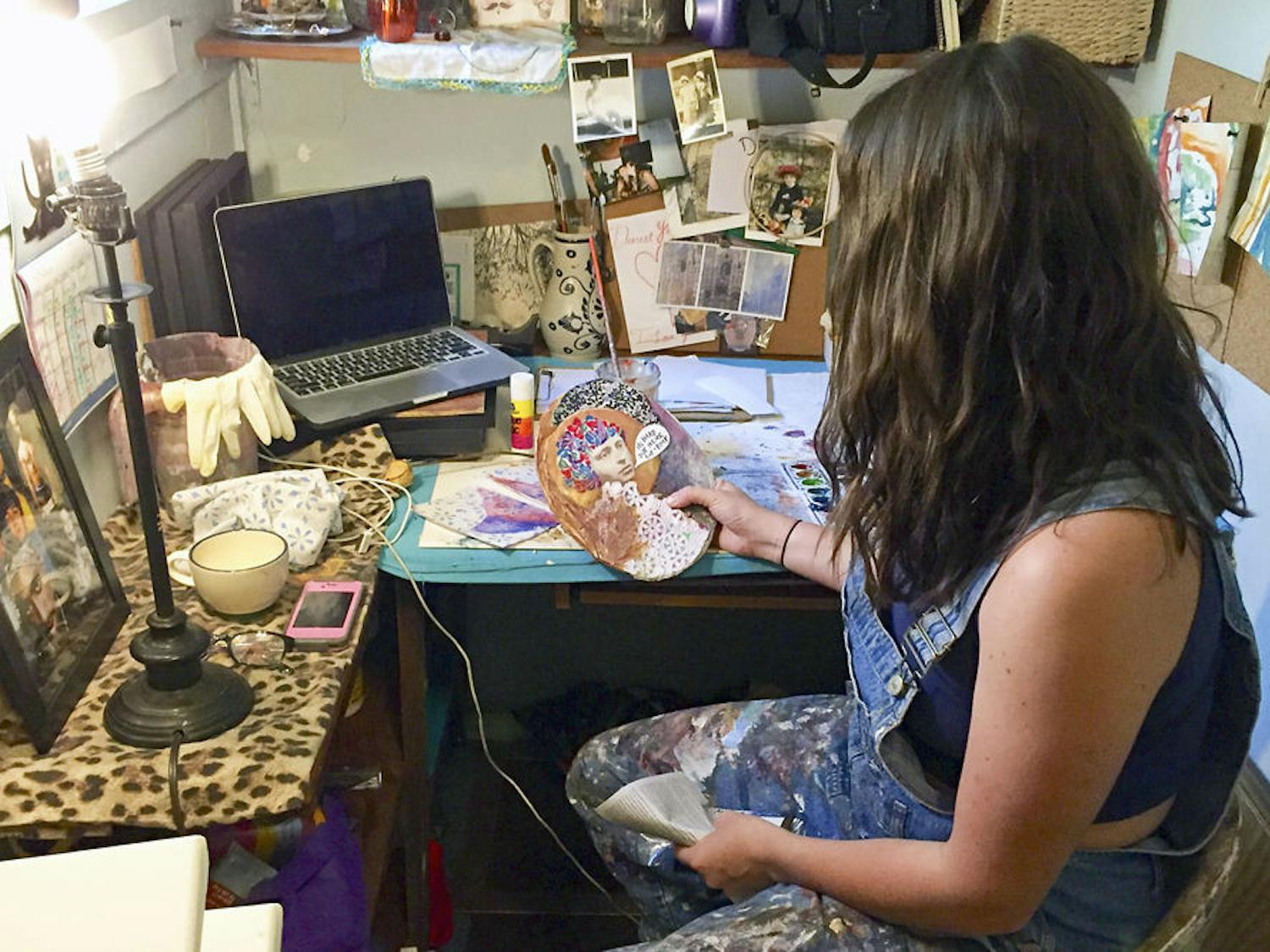 Horner examines one of her pieces in her Gainesville studio; though she makes art to sell, she also makes art for pleasure, like the piece she holds.