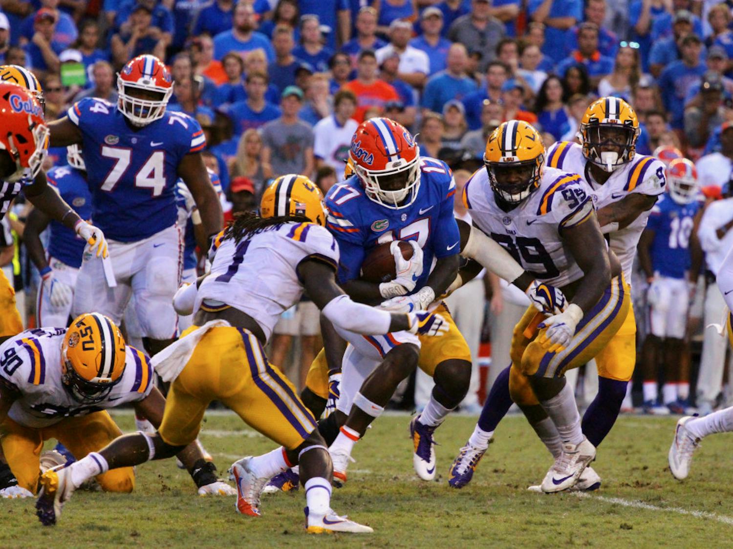 Gators athlete Kadarius Toney is wrapped up by LSU defenders.