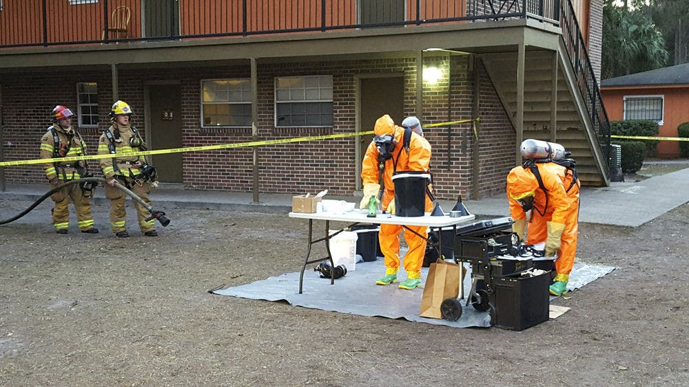 <p>Hazmat workers examine meth lab equipment found inside Village Green Apartments on Tuesday. Police arrested two Gainesville residents they said produced the drug in the same apartment as a 5-year-old boy.</p>