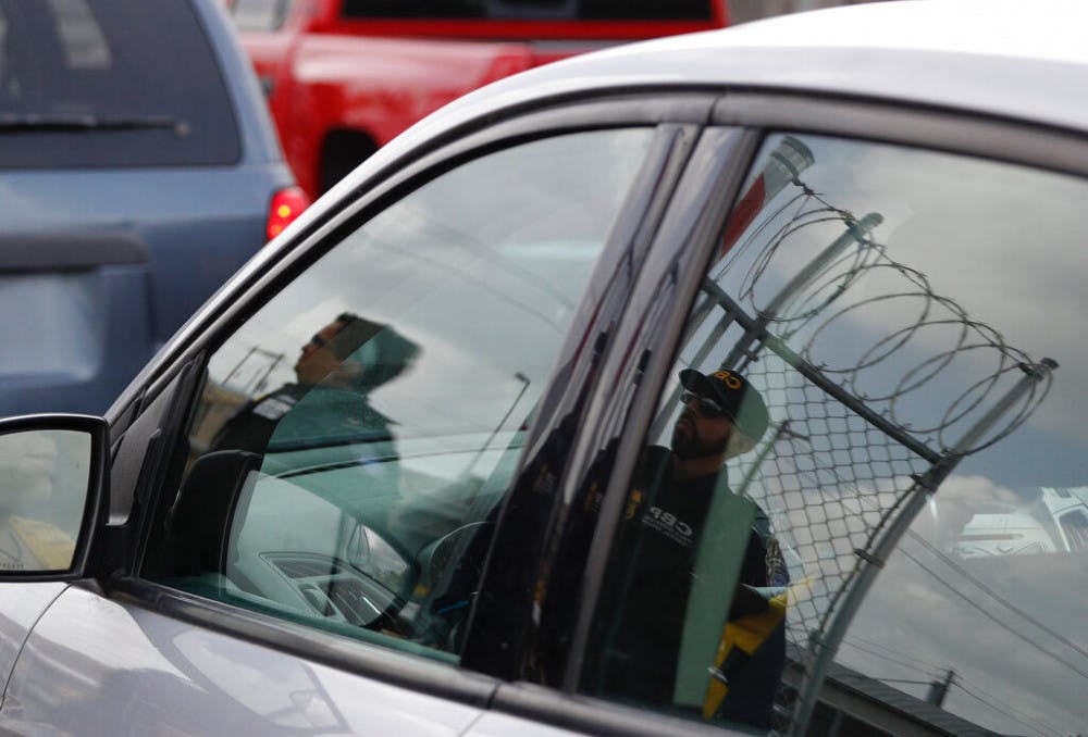 Customs and Border Protection agents are reflected in the window of an entering car, as they survey vehicles entering the U.S. on the Puerta Mexico international bridge leading into Brownsville, Texas from Matamoros, Mexico, Friday, June 28, 2019. Hundreds of migrants from Central America, South America, the Caribbean and Africa have been waiting for their number to be called at the bridge in downtown Matamoros, to have the opportunity to request asylum in the U.S.