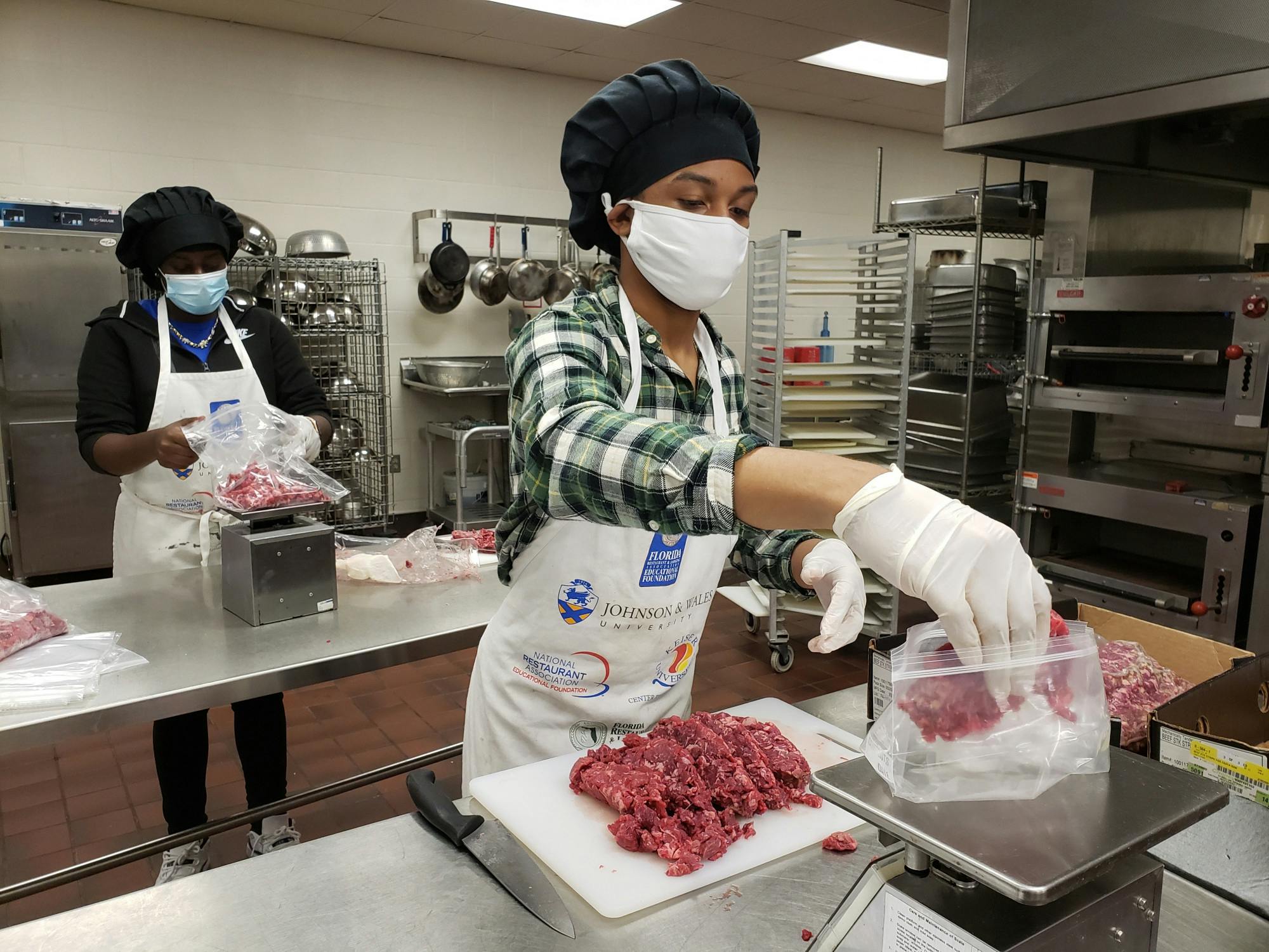 Eastside High students Khyeisha Boykins and Jay&#x27;Marlon Wilson prepare food for eligible families [Photo courtesy of Alachua County Public Schools Spokesperson Jackie Johnson]. 
