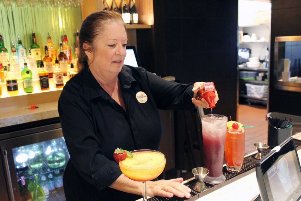 Erin Gosselin tops off a drink with Coca-Cola before handing it to a server Thursday. Gosselin is a bartender at the Olive Garden Italian Restaurant on Clark Butler Boulevard.
