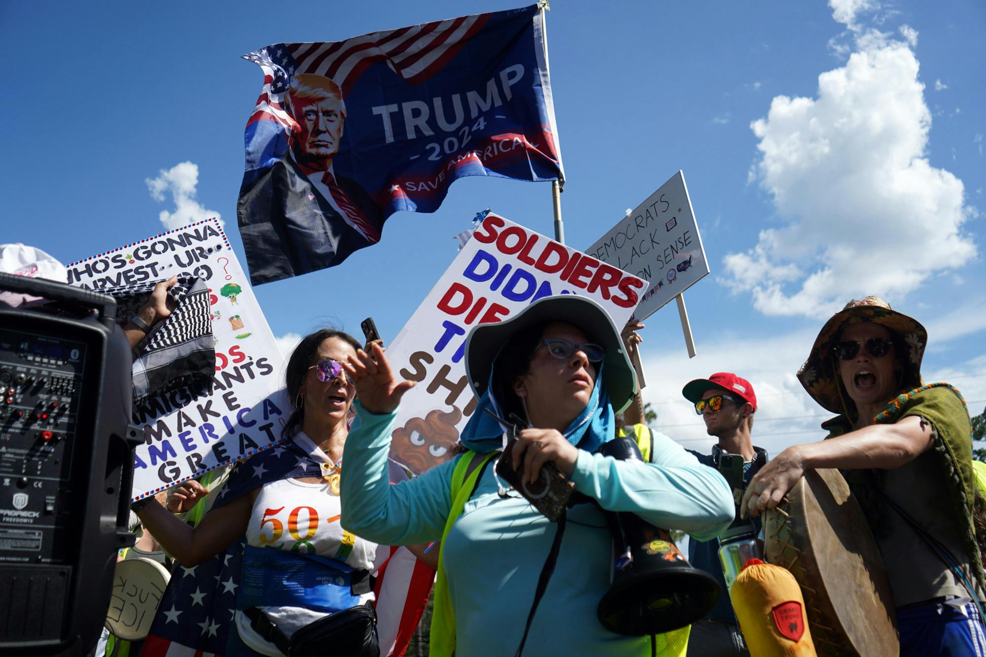 Counter protesters for the Stop Camp Blanding Protest raise a flag and sign while protesters chant and an organizer encourages other not to engage with them in Starke, Fla., on Saturday, July 19, 2025.