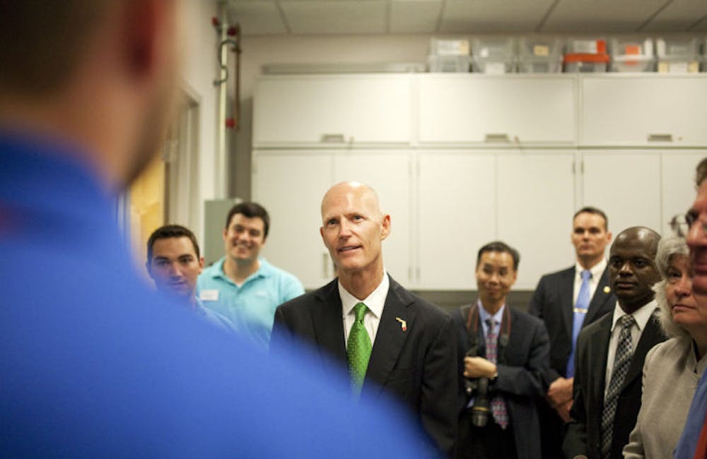 <p>Gov. Rick Scott speaks to a UF senior during his tour of the university’s Nanoscale Research Facility. Scott plans to give UF about $15 million annually for the next five years.</p>