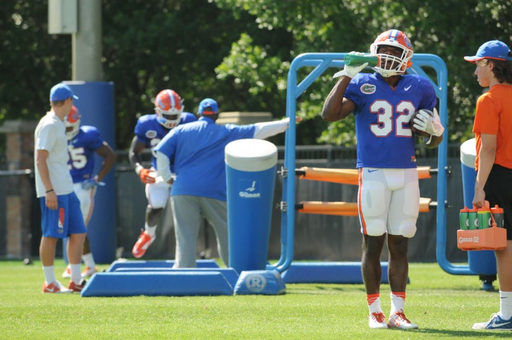 Jordan Cronkrite (32) takes a break from Florida's Spring practice while running backs coach Tim Skipper (middle) watches Mark Thompson (24) run drills. The Gators practiced for two hours at the Sanders Practice Fields on March 30.