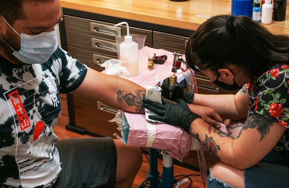 Kristyn Lopez, 37, (right) gives a tattoo designed to emulate a tarot card to Franciso Martinez, 31, a Gainesville resident (left) on Sunday, June 13, 2021.
