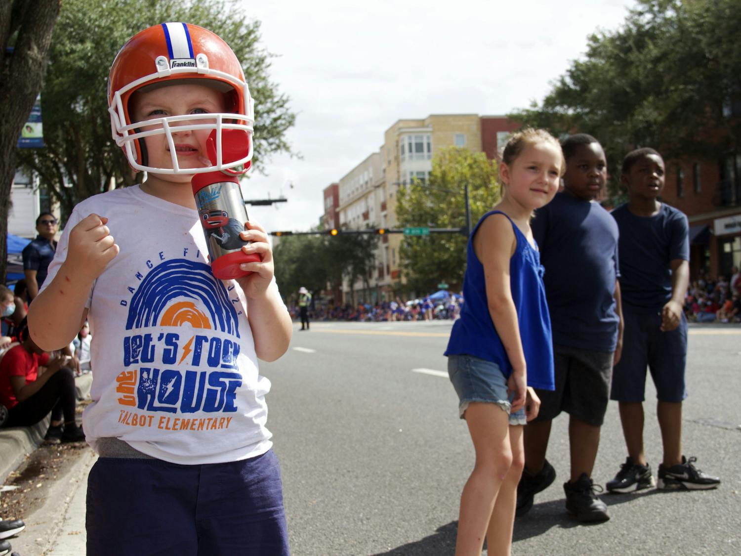 Gavin Hughes (left), Haddie Hughes (middle), and twins Emanuel and Elijah Harmon (right) watch the UF Homecoming Parade approach on University Avenue on Friday, Oct. 8, 2021.