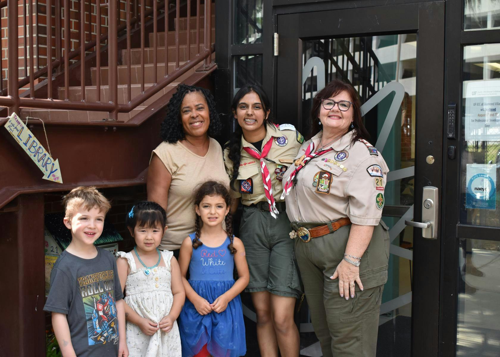 Dawne Morison (left), Eagle Scout Kaayana Sharma (middle), and Scouts Master Kim Lovelady (right) stand with Baby Gators in front of the newly installed lending library, Thursday, July 30, 2026, at the UF Early Childhood Collaboratory at Diamond Village, in Gainesville, Fla.