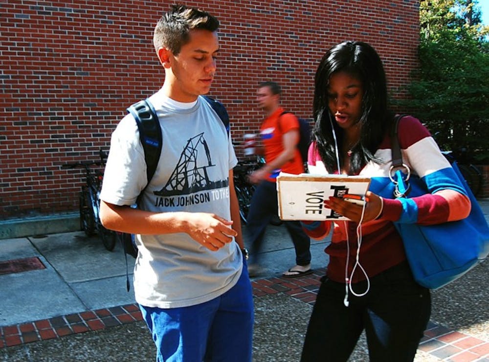 <p>Sport management sophomore Joe DaSilva, 19, helps Rolanda Charles, 18, get registered to vote on Monday afternoon.</p>