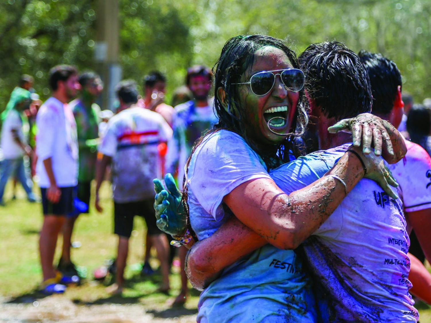 From left: Simran Giri, 19, a UF microbiology and cell science freshman who is originally from India, hugs her friend during the UF Holi Festival of Colors on Sunday afternoon. After the kickoff, many people went under water thrown by a fire truck. A mud fight followed. 