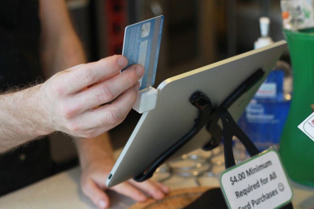 <p>A Karma Cream employee swipes a credit card on an iPad card reader to complete a transaction Wednesday. Business owners cite portability and saving space as benefits to using the card readers.</p>