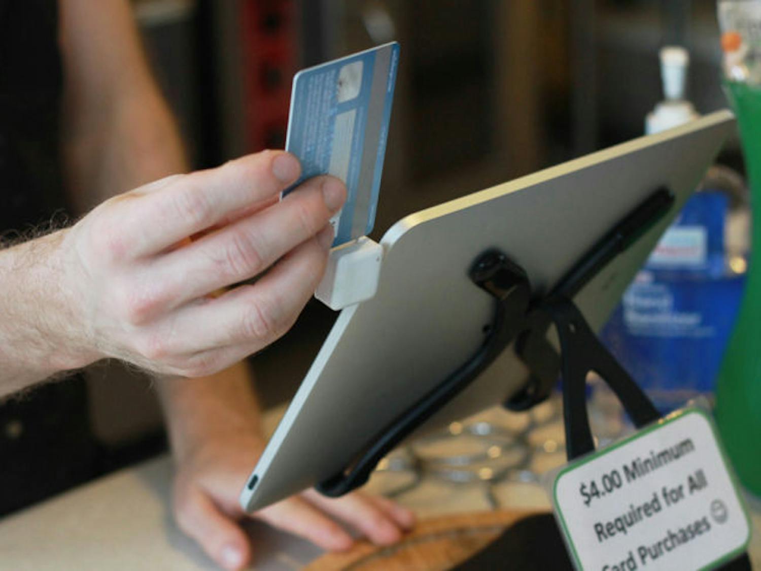 A Karma Cream employee swipes a credit card on an iPad card reader to complete a transaction Wednesday. Business owners cite portability and saving space as benefits to using the card readers.